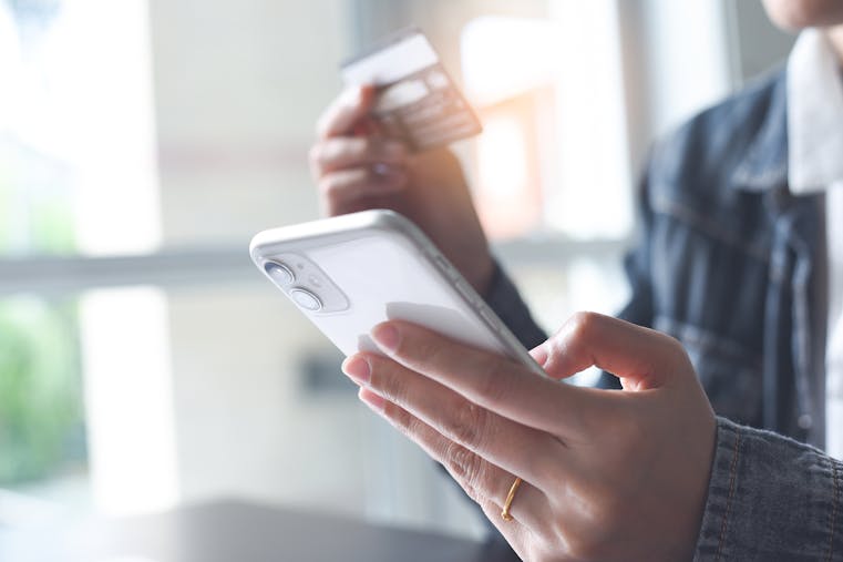 Online shopping, digital banking, E-commerce concept. Woman hand using mobile smart phone, tablet payments and holding credit card online shopping with laptop computer on table