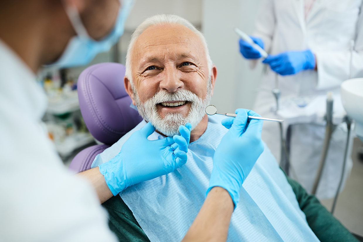 Happy mature man during teeth check-up at dental clinic.